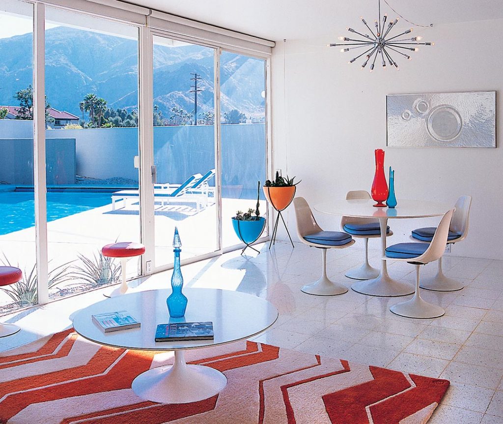 a midcentury modern dining room in a Wexler home in Palm Springs. White terrazo floors gleam and mirro the white Saarinen tupil table and chairs dining set. A chrome sputnik light hangs above. 