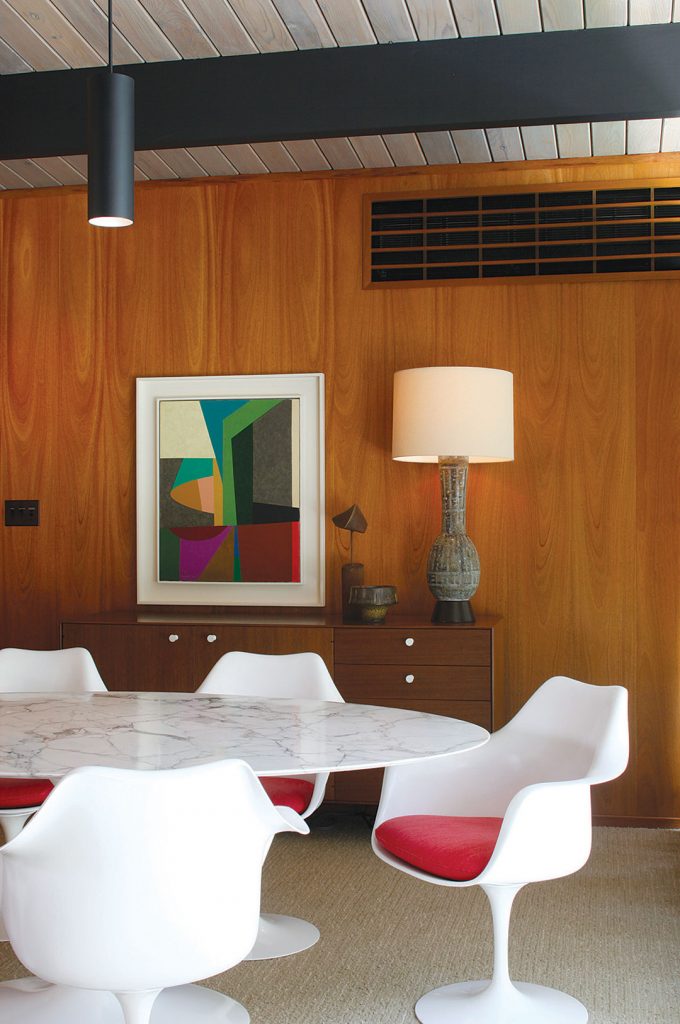 mid century modern dining room of and Eichler house with walnut wall paneling and a Saarinen tulip table and chairs dining set