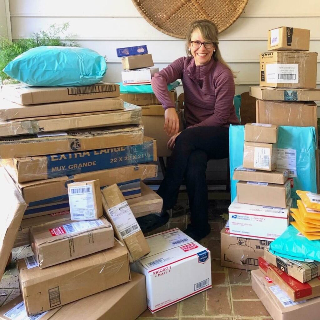 A vintage seller is surrounded by dozens of packages she's going to ship out to customers.