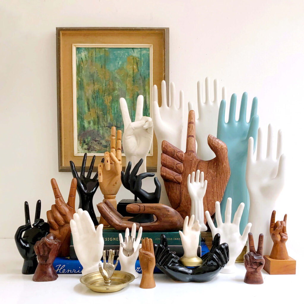 A collection of vintage hand sculptures made of wood, porcelain and plastic.