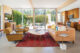 concrete floors with red rug, corduroy chairs and leather couch in living room