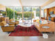 concrete floors with red rug, corduroy chairs and leather couch in living room