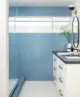 bathroom with blue tile wall, terrazzo floor, white vanity and black counter top in 1957 renovated ranch