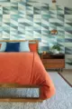 multi-colored blue green diamond wallpaper and orange bedding in 1957 ranch