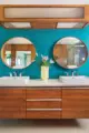 primary bathroom with floating wood vanity teal grasscloth wallpaper and rounded mirrors