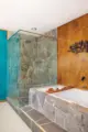 wood paneled accent wall with natural stone walls surrounding shower and tub in 1971 Oregon ranch home