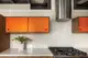 orange sliding cabinet fronts and round vent hood in Pacific Northwest home's renovated kitchen