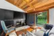 black fireplace surround and wooden sloped ceiling with view to renovated landscape in Portland home