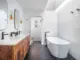 master bath with wood vanity black hexagonal tile and soaking tub