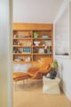 tan Womb chair and ottoman next to built-in bookshelves and storage cabinets in renovated MCM home