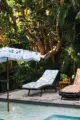 fringed retro style umbrella and floral cushions with pom pom fringe near backyard pool