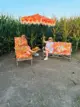 Alex and Jules of Hazy Sunshine sitting on outdoor decor with their colorful cushions and with their fringed umbrella