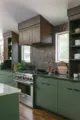 renovated modern kitchen with expanded footprint, green cabinetry and wood surround for oven hood