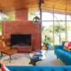 living room with brick fireplace and tan Eames lounge chair